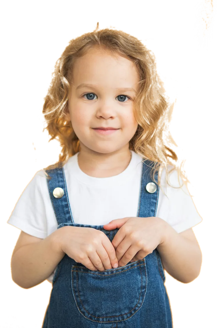 A young girl in denim overalls smiling at the camera